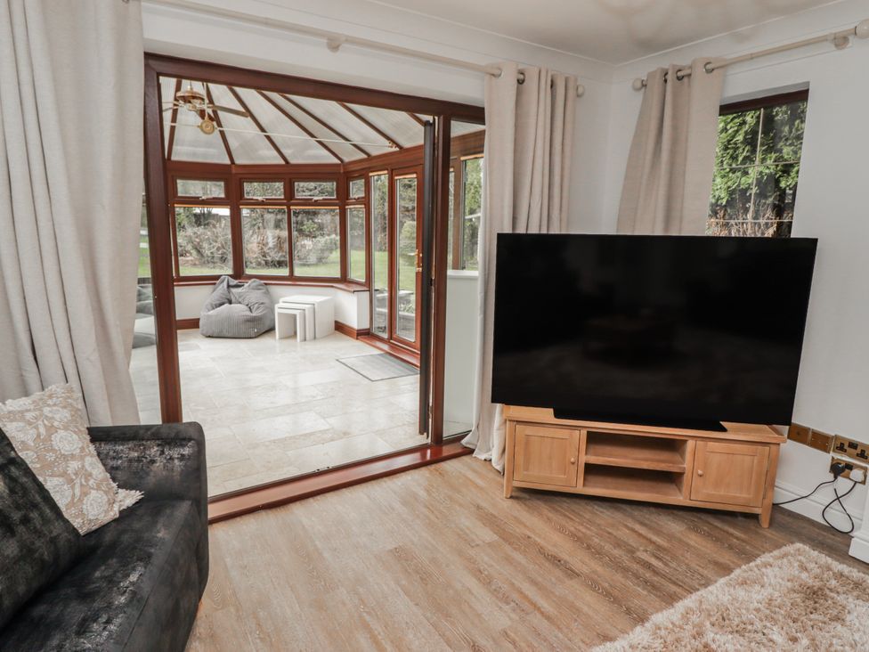 A conservatory with a television and sofa at Carreg Llwyd in Groeswen near Trecenydd