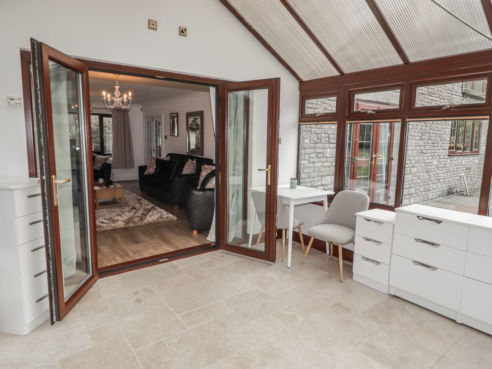 A conservatory with doors and furniture at Carreg Llwyd in Groeswen near Trecenydd