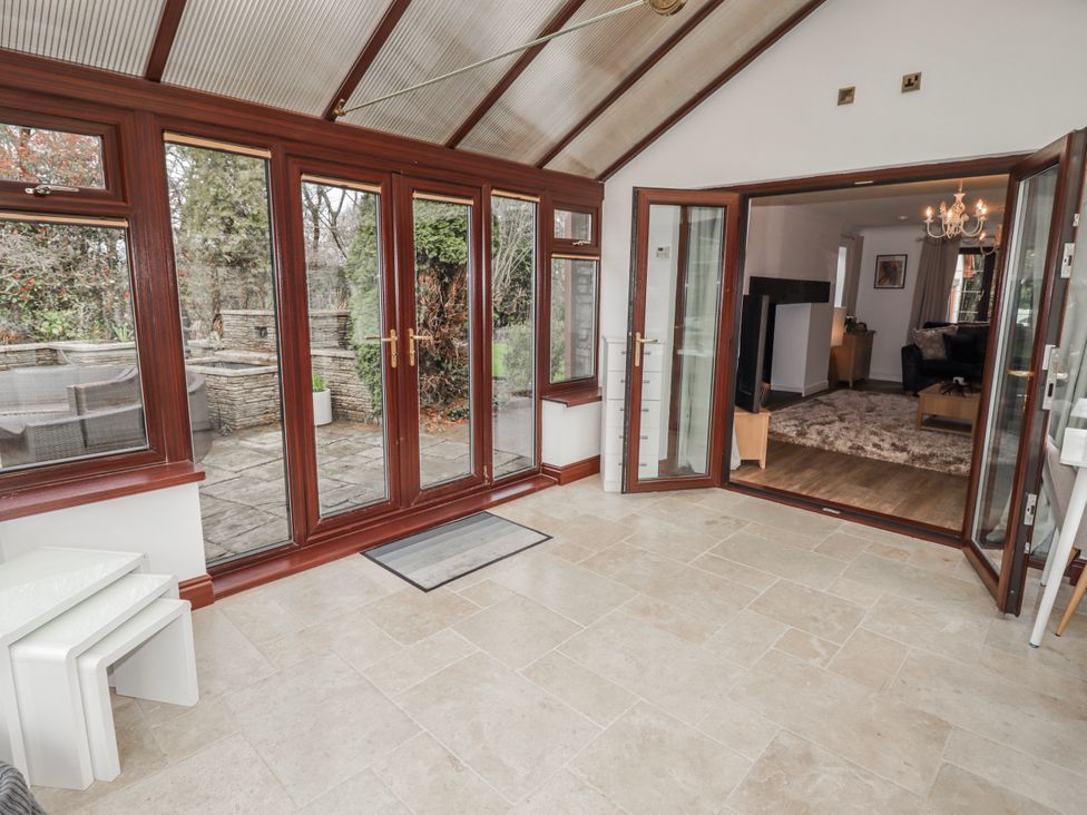 A conservatory with large windows and seating area at Carreg Llwyd in Groeswen near Trecenydd