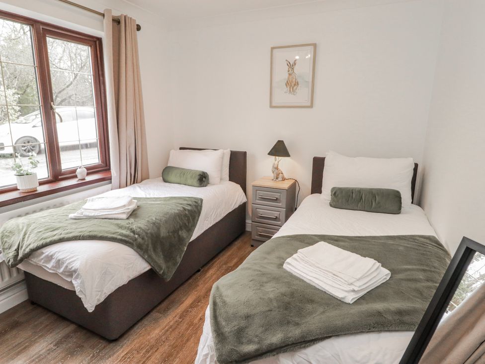 A bedroom with two beds and a lamp at Carreg Llwyd Groeswen near Trecenydd
