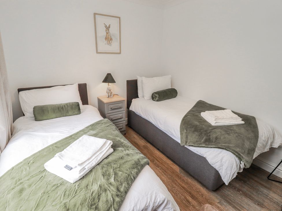 A bedroom with two beds and a bedside table at Carreg Llwyd Groeswen near Trecenydd