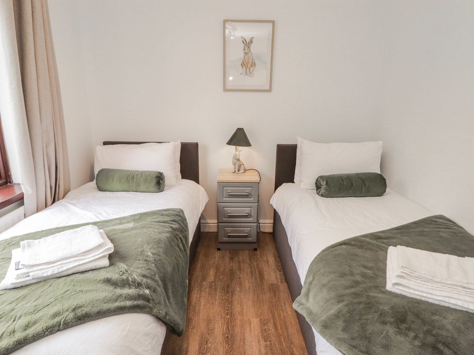 A bedroom with two single beds and a nightstand at Carreg Llwyd in Groeswen near Trecenydd