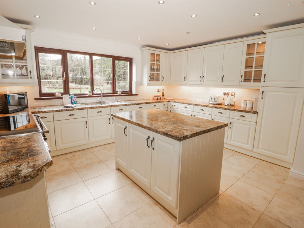 A kitchen with an island and cabinets at Carreg Llwyd Groeswen near Trecenydd