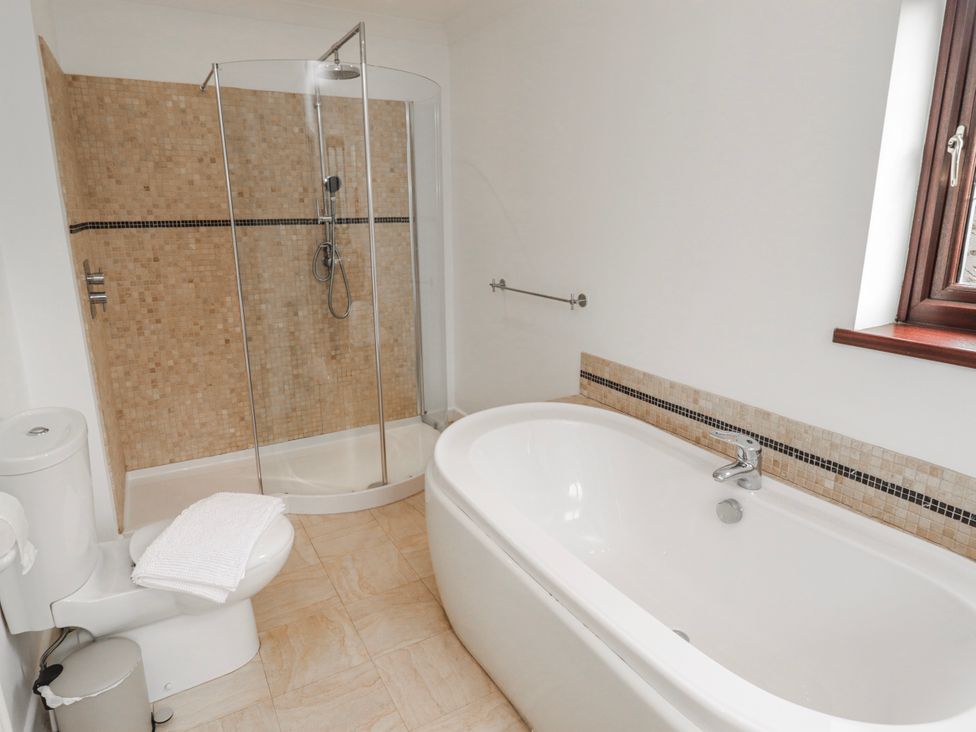 A bathroom with a shower, bathtub, and toilet at Carreg Llwyd in Groeswen near Trecenydd