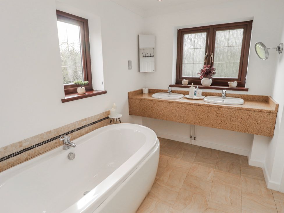 A bathroom with a bathtub and sinks at Carreg Llwyd in Groeswen near Trecenydd