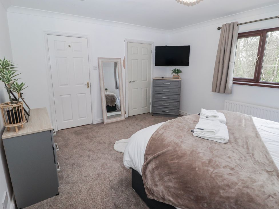 A bedroom with a bed, television, mirror, and dresser at Carreg Llwyd near Groeswen Trecenydd