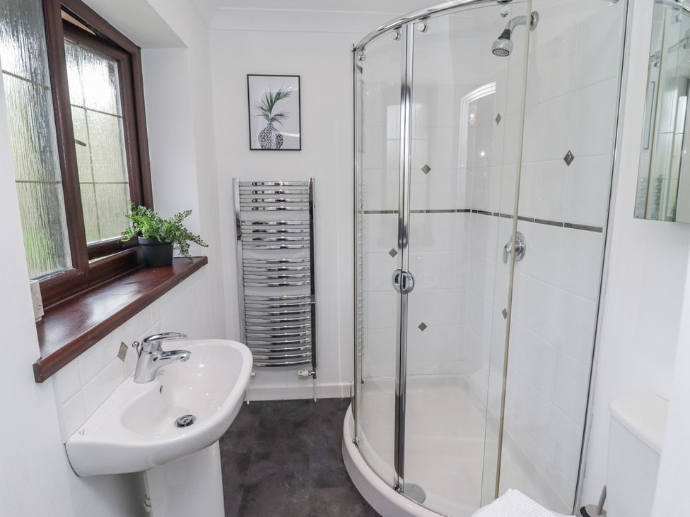 A bathroom with a sink, shower, and towel radiator at Carreg Llwyd near Trecenydd