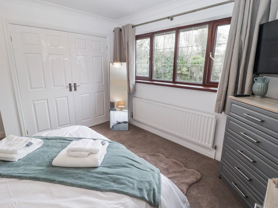 A bedroom with a bed and mirror at Carreg Llwyd in Groeswen near Trecenydd