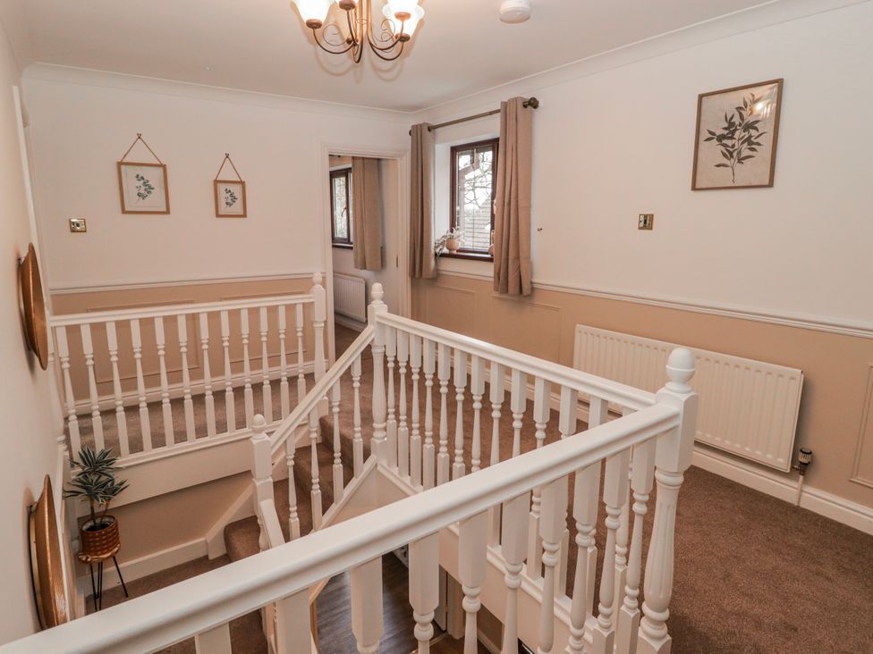 A hallway with a staircase and framed pictures at Carreg Llwyd in Groeswen near Trecenydd