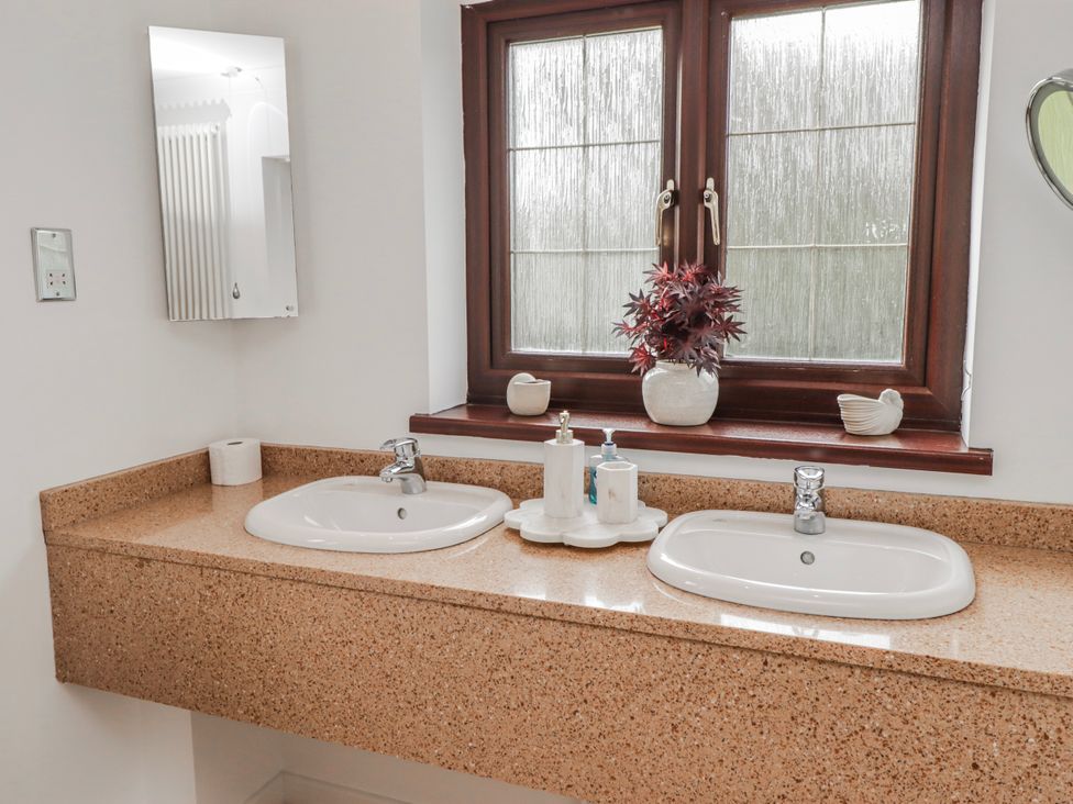 A bathroom with dual sinks and a window at Carreg Llwyd Groeswen near Trecenydd