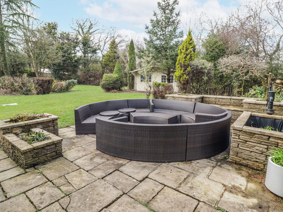 An outdoor seating area with a circular sofa and table at Carreg Llwyd Groeswen near Trecenydd