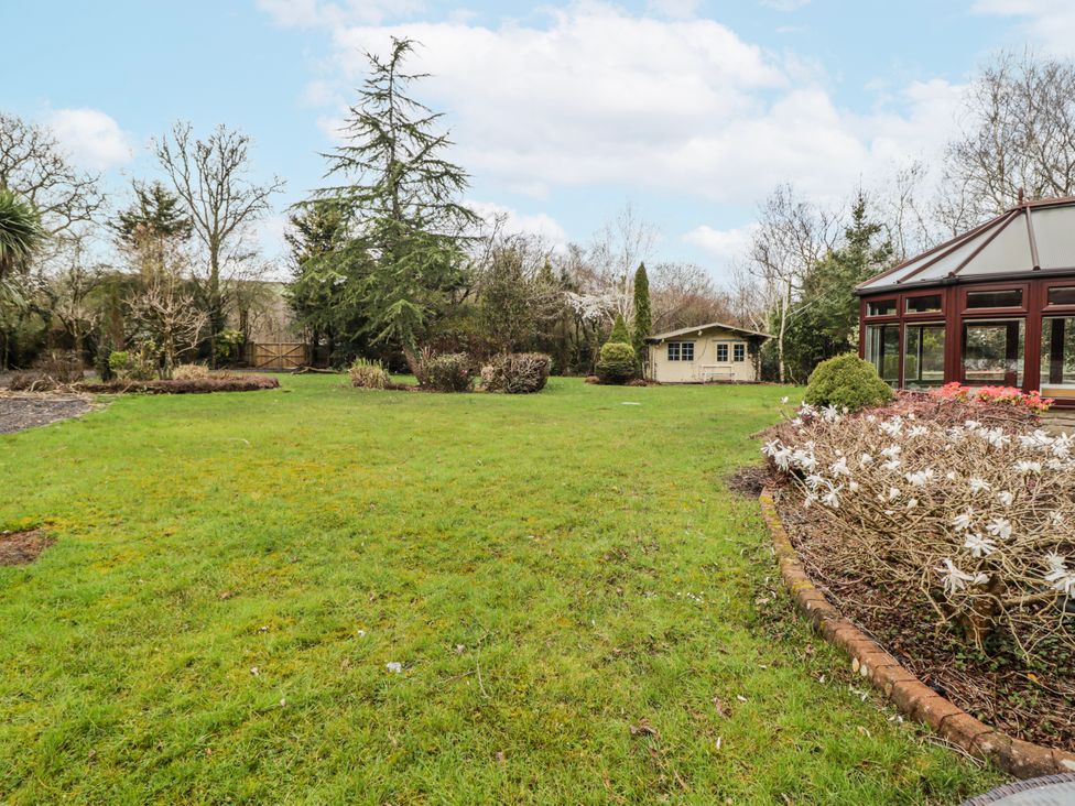 A garden with grass, trees and a shed at Carreg Llwyd in Groeswen near Trecenydd