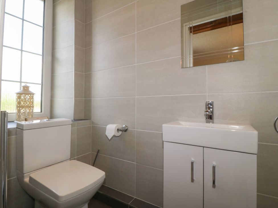 A bathroom with a toilet sink and mirror at Glasfryn in Llandwrog