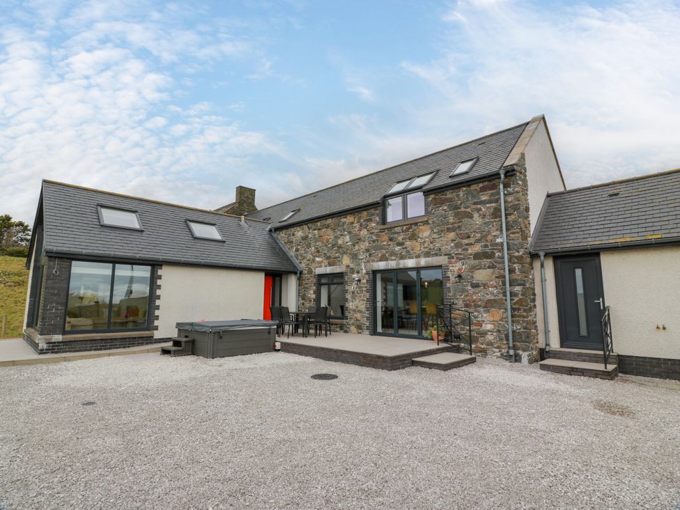 An outdoor view of a house with a hot tub at Balcarry Barn Glenluce