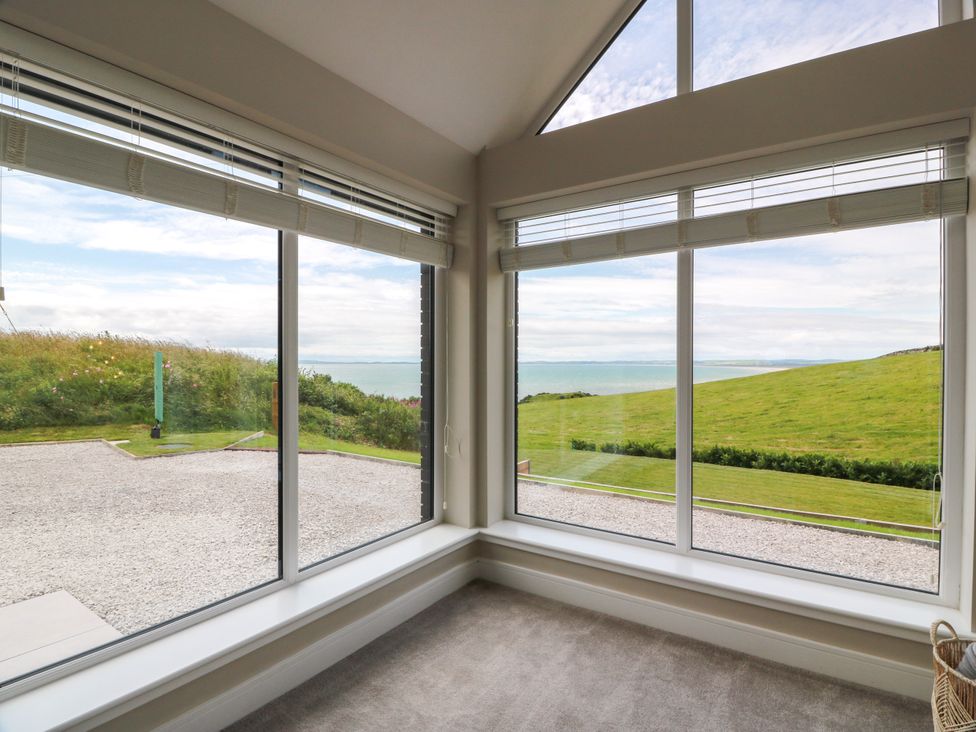 A living room with windows overlooking grass and ocean at Balcarry Barn in Glenluce