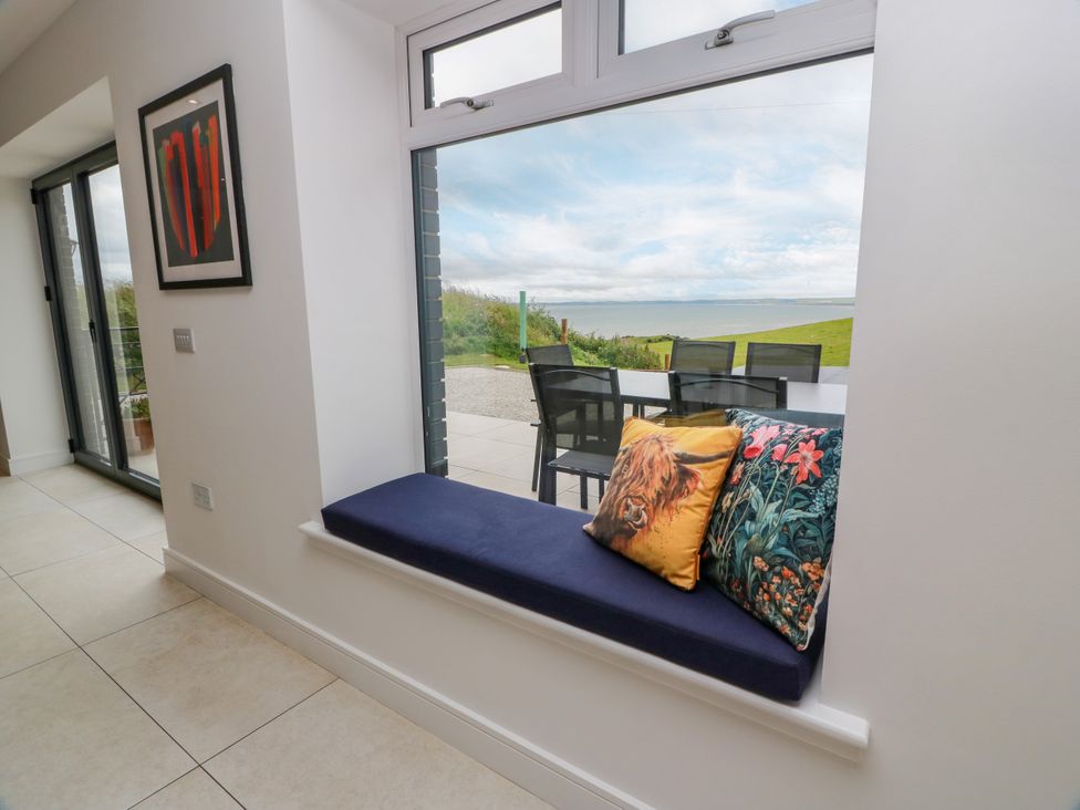 A living room with a seat and view to the outdoor patio at Balcarry Barn in Glenluce