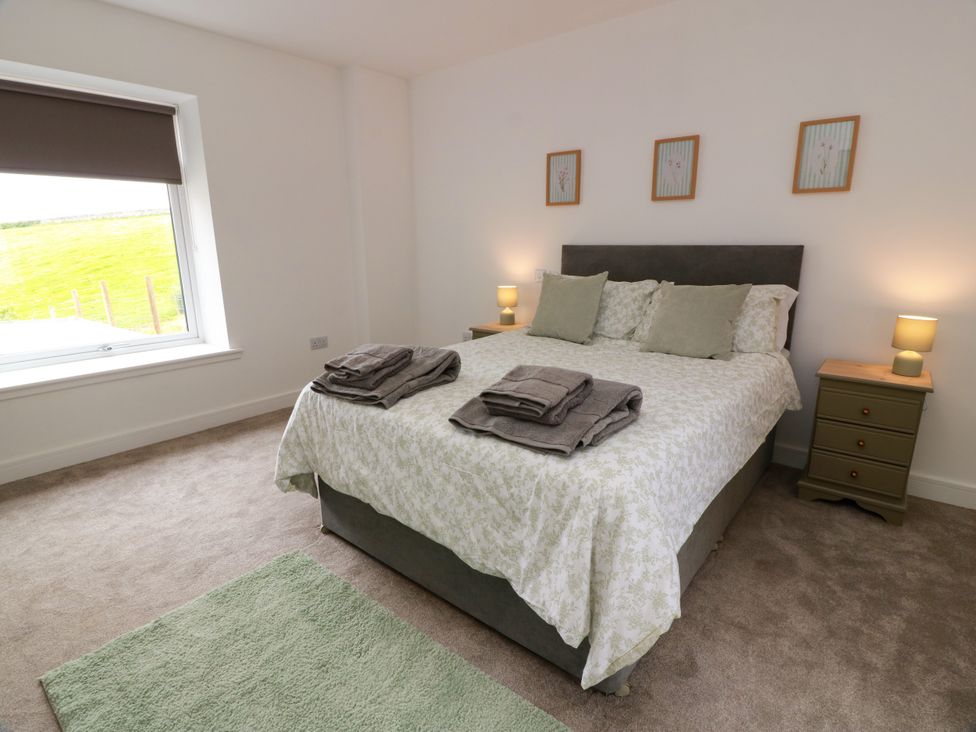 A bedroom with a bed, bedside tables, and lamps at Balcarry Barn Glenluce