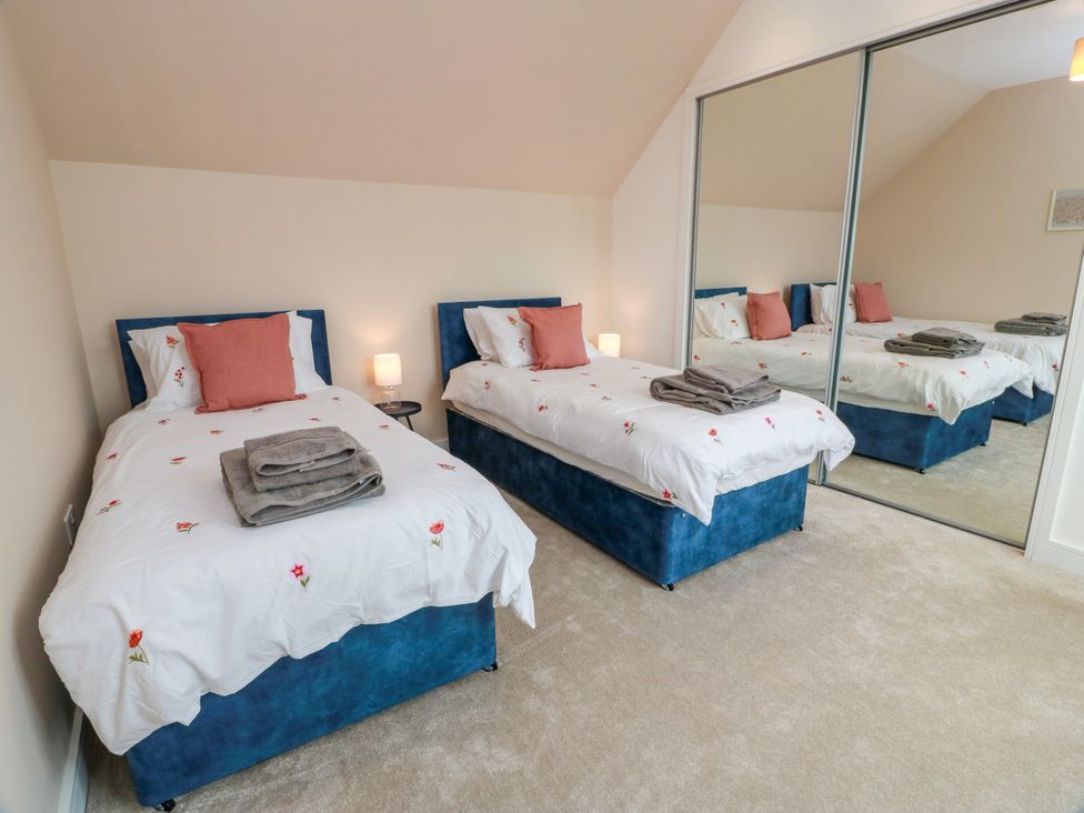 A bedroom with two beds and a mirror at Balcarry Barn in Glenluce