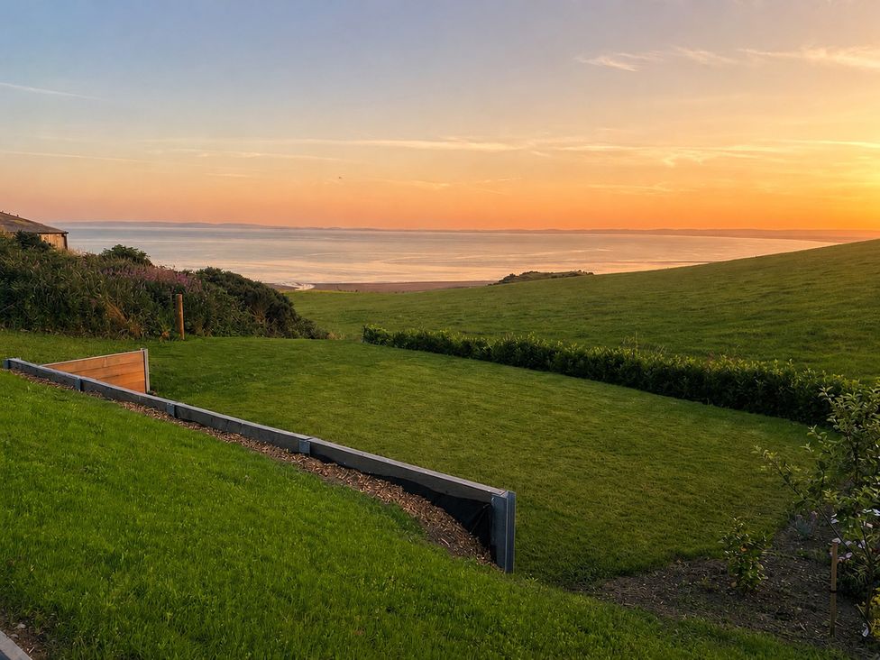 A garden with grass and a view of the ocean at Balcarry Barn near Glenluce