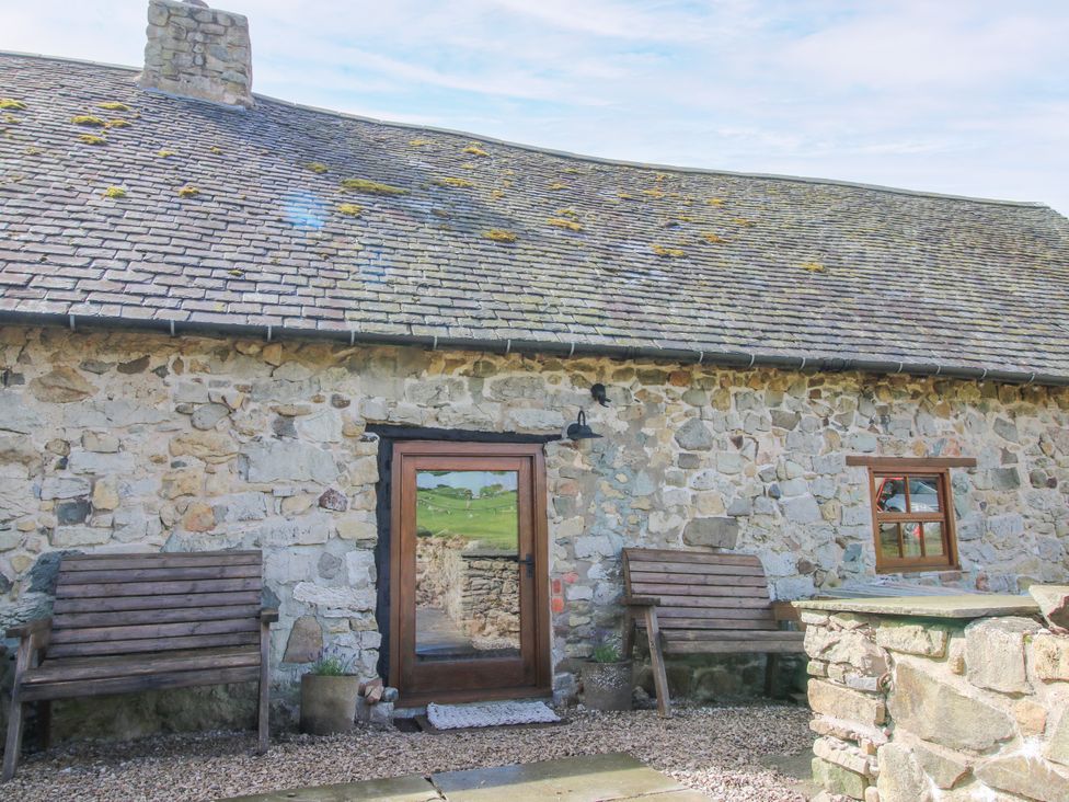 An outdoor area with a stone wall and benches at The Long House near Trefonen
