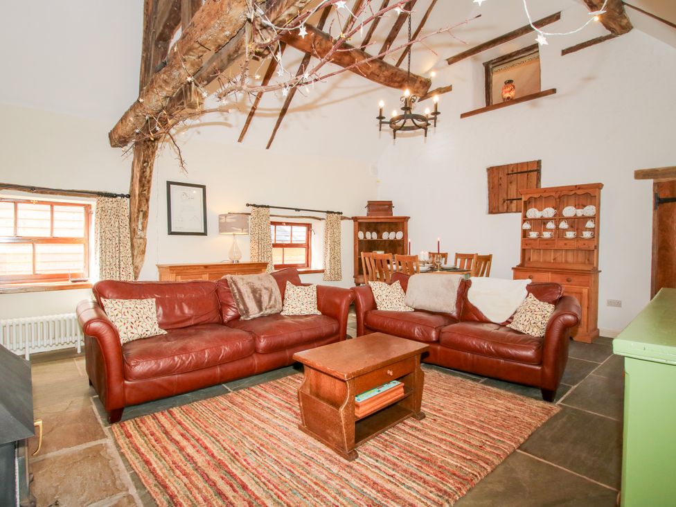 A living room with leather sofas and a dining area at The Long House near Trefonen