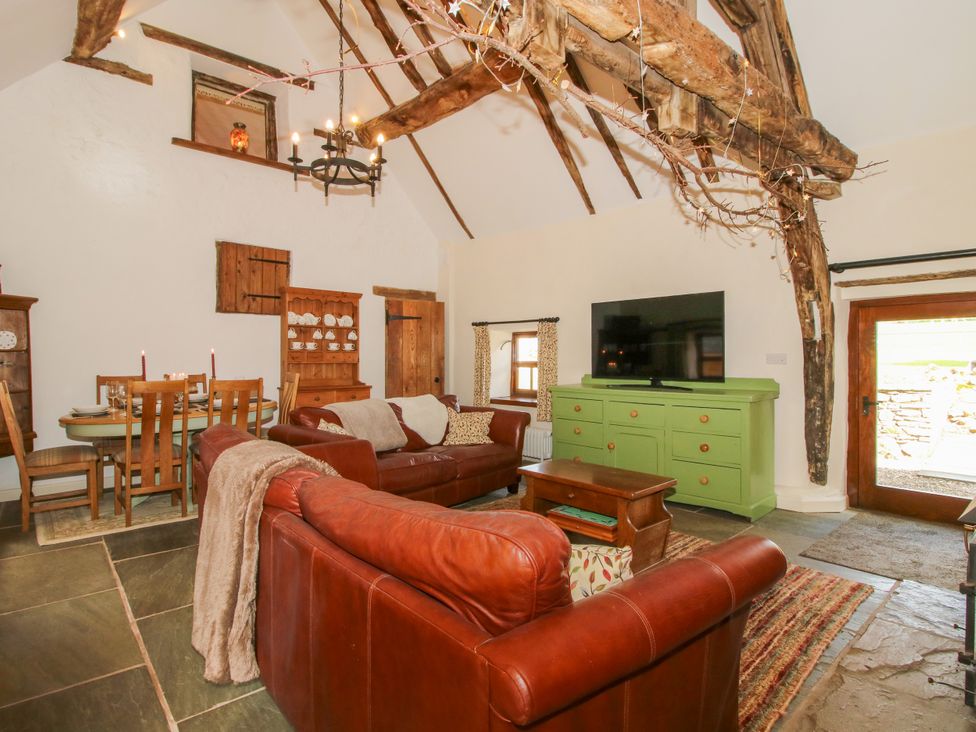 A living room with leather sofa and a dining table at The Long House near Trefonen