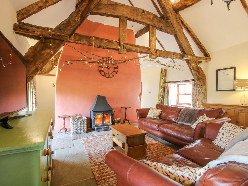 A living room with leather sofas and a fireplace at The Long House near Trefonen