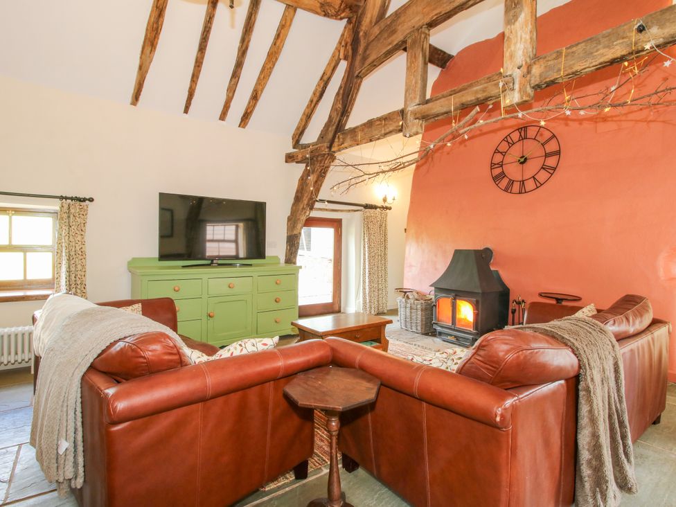 A living room with a television and a fireplace at The Long House Near Trefonen