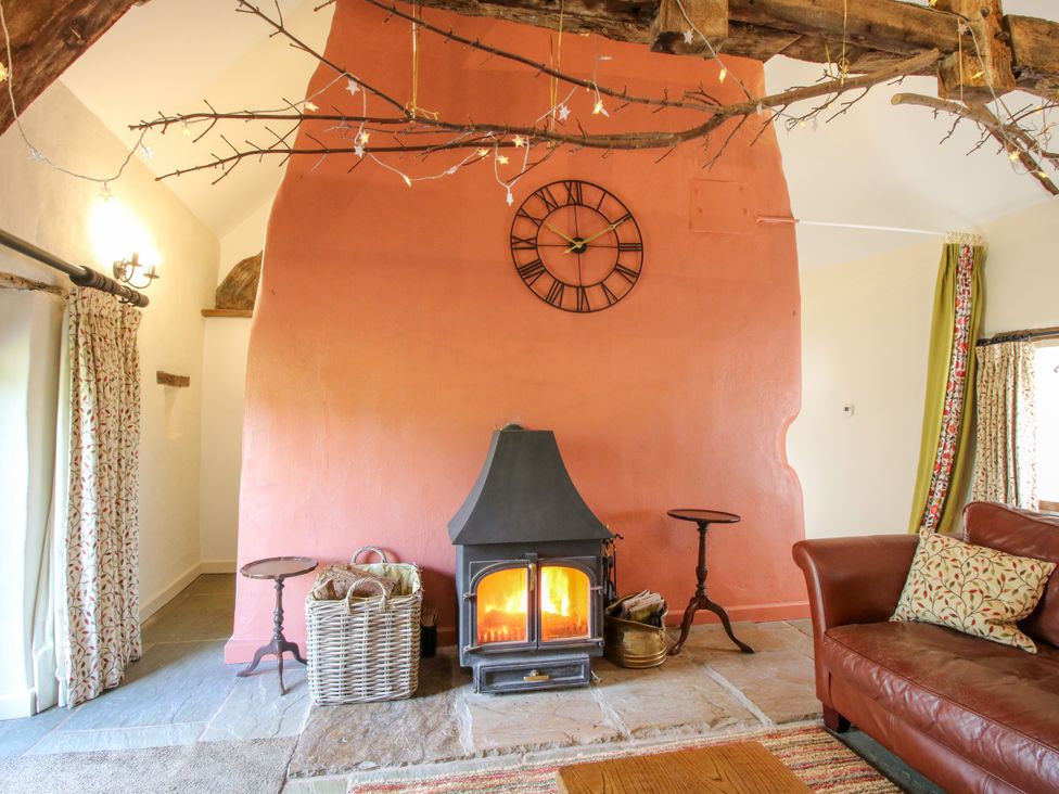 A living room with a fireplace and sofa at The Long House near Trefonen