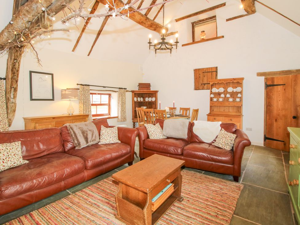 A living room with leather sofas and a dining area at The Long House near Trefonen