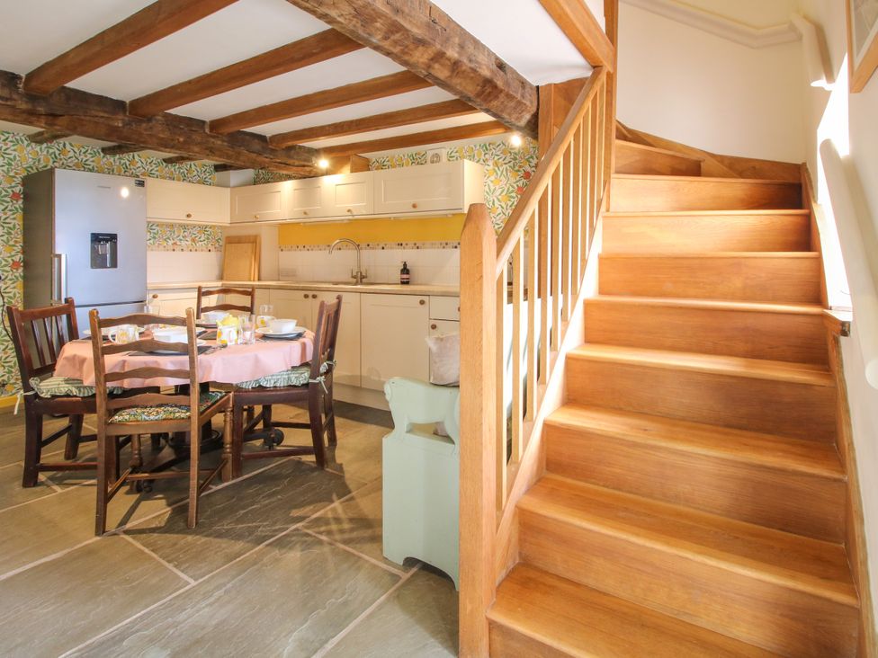 A kitchen with a dining table and staircase at The Long House near Trefonen