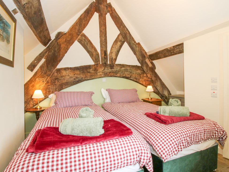A bedroom with two beds and wooden beams at The Long House Near Trefonen