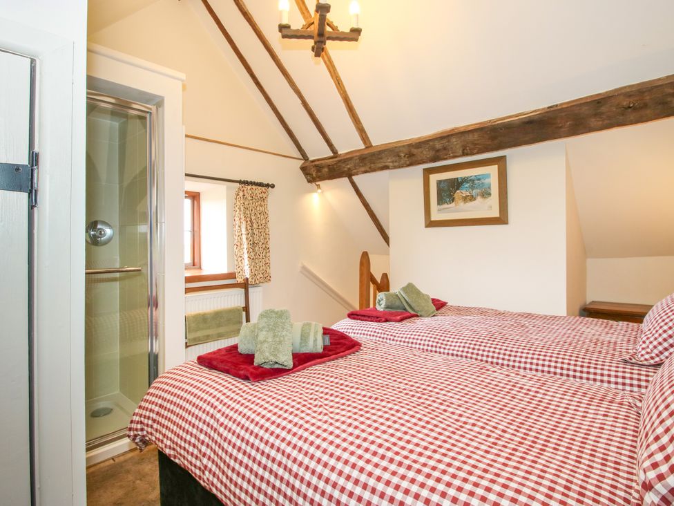 A bedroom with two beds and a shower room at The Long House near Trefonen