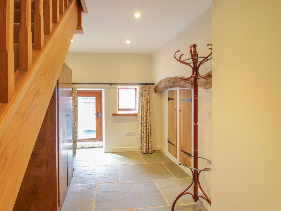 A hallway with a coat rack and a window at The Long House near Trefonen