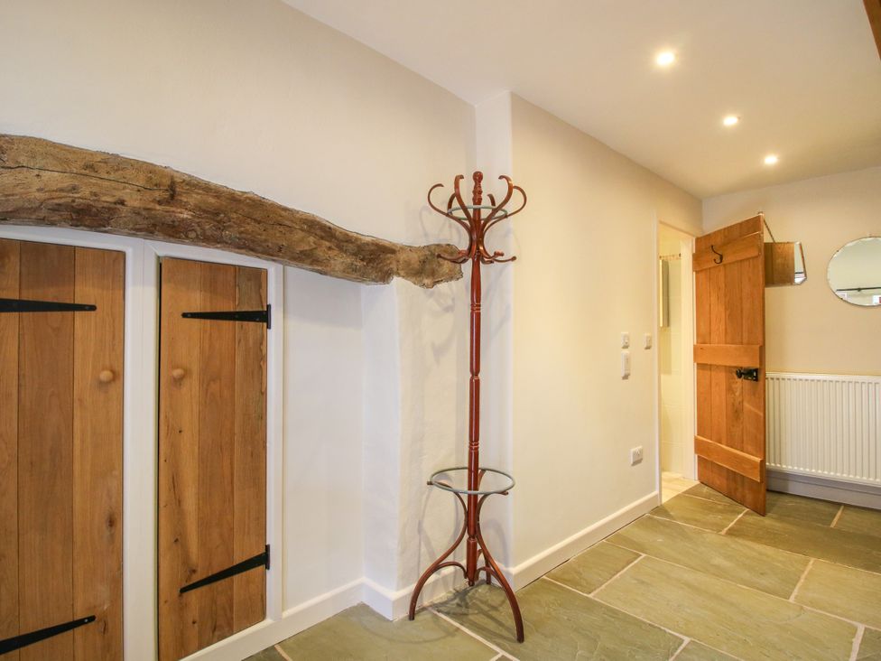 A hallway with a coat rack and wooden doors at The Long House Near Trefonen