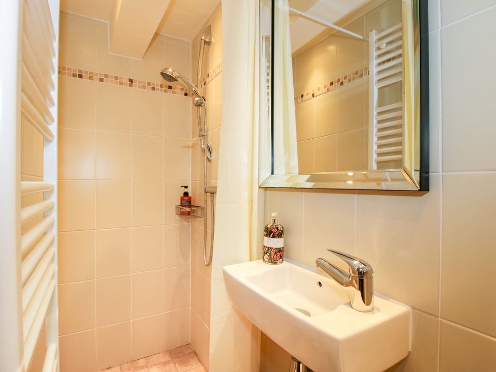 A bathroom with a shower, sink and mirror at The Long House Near Trefonen