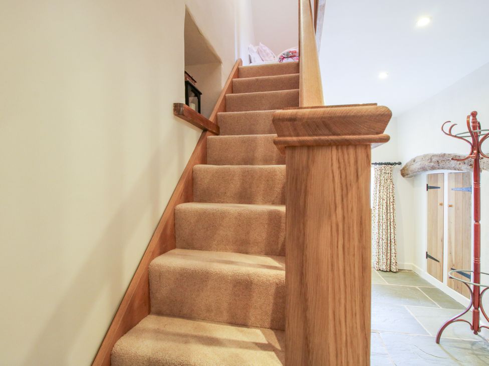 A staircase with a handrail and carpet at The Long House near Trefonen