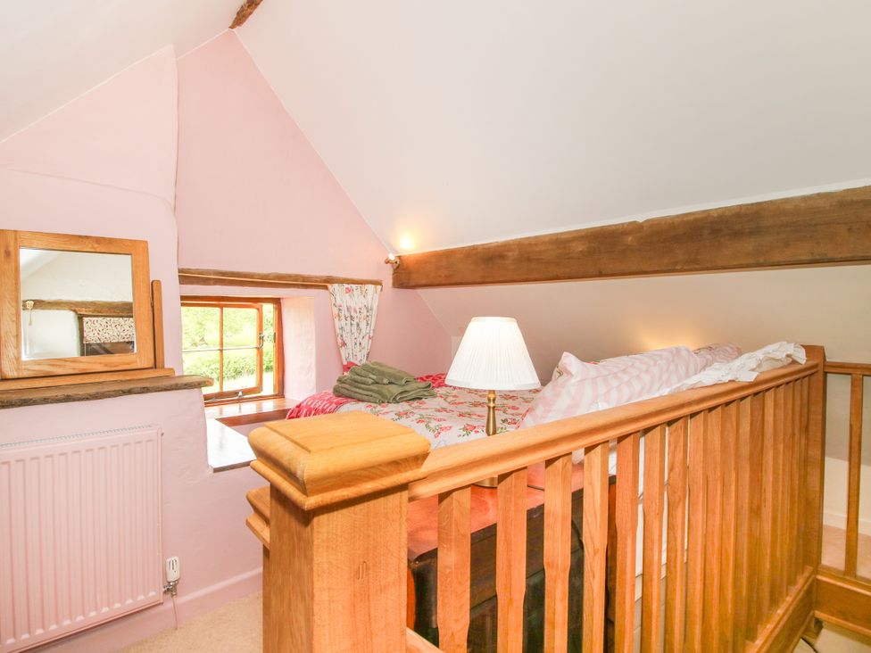 A loft bedroom with a bed and mirror at The Long House Near Trefonen