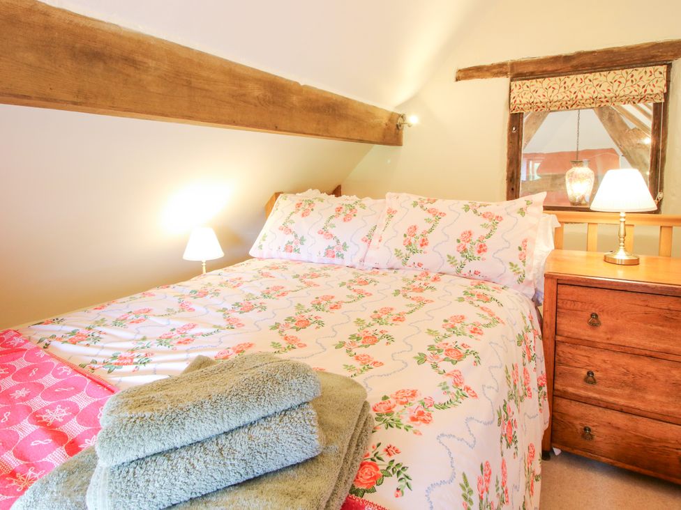 A bedroom with a bed and nightstand at The Long House near Trefonen