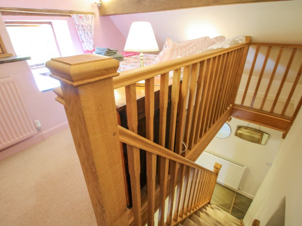 A staircase with a wooden railing and a lamp at The Long House near Trefonen