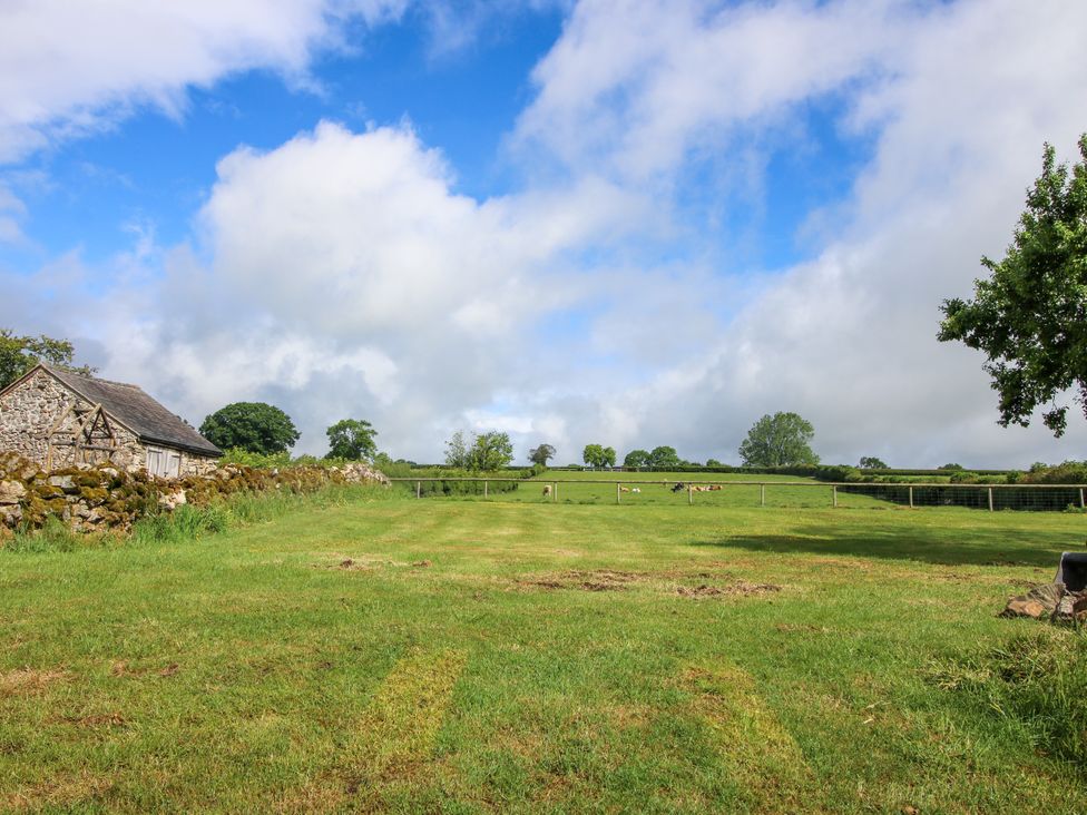A field with a stone building and trees at The Long House Near Trefonen