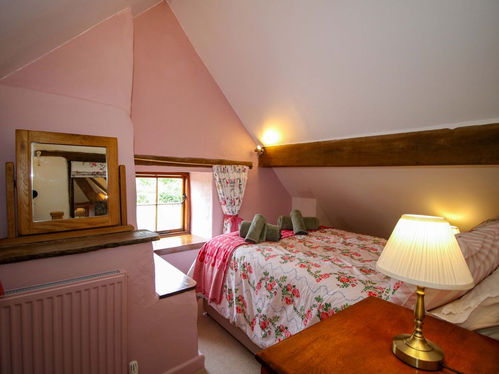 A bedroom with a bed, lamp, and window at The Long House Near Trefonen