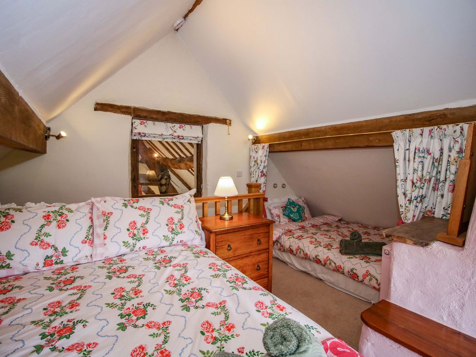 A bedroom with two beds and wooden furniture at The Long House Near Trefonen