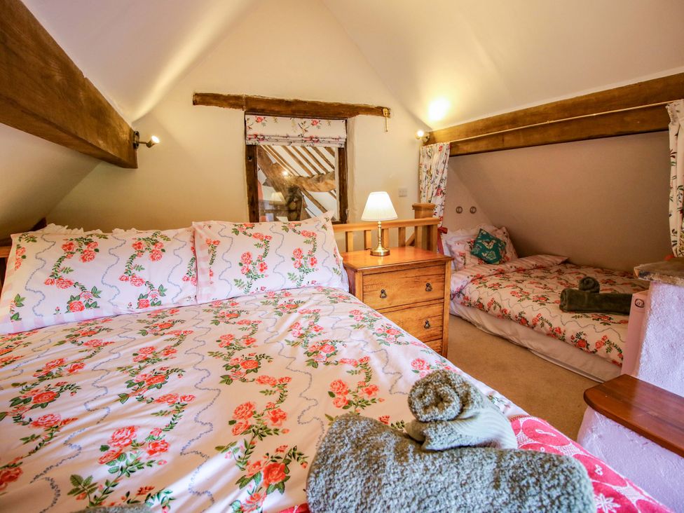 A bedroom with two beds and a bedside table at The Long House Near Trefonen