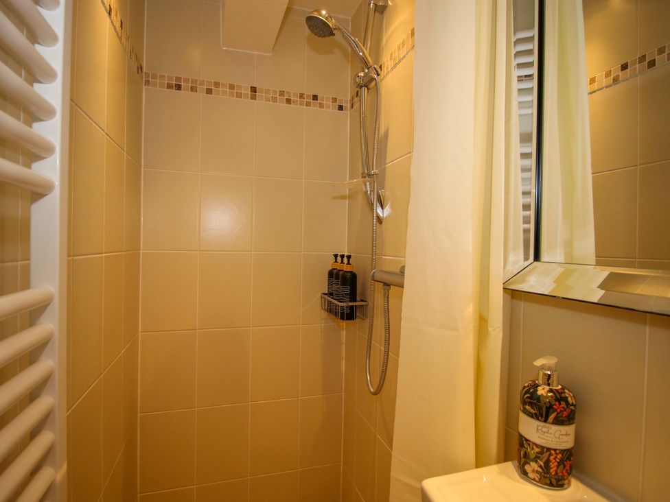 A shower with a handheld showerhead and shelf in The Long House near Trefonen