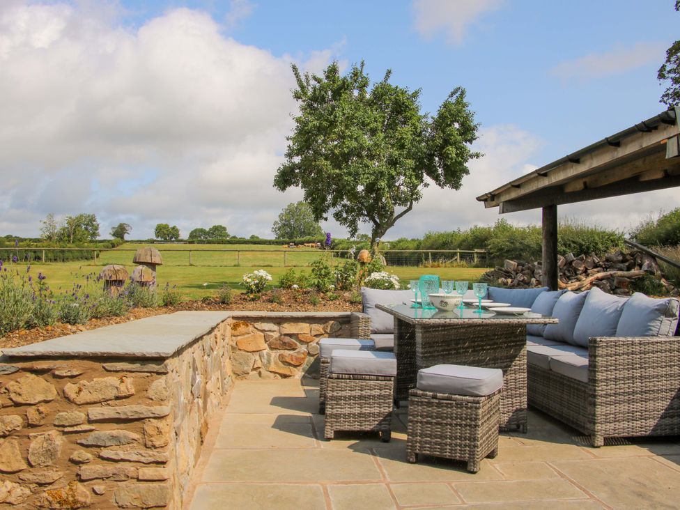 An outdoor patio area with seating and a table at The Long House Near Trefonen