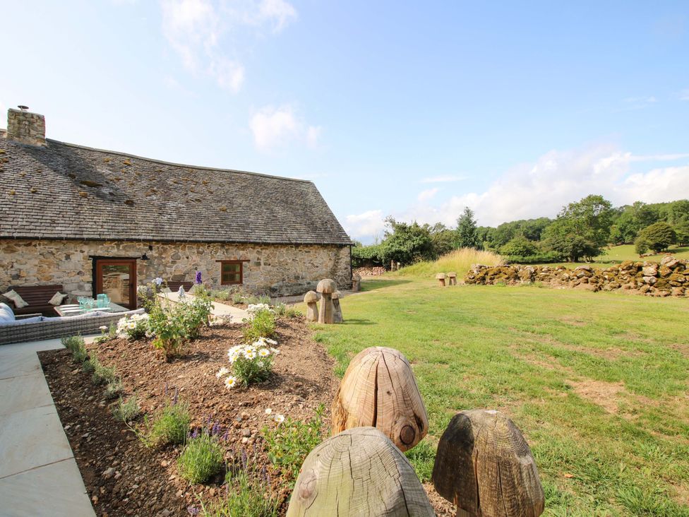 An outdoor area with a stone building and garden at The Long House near Trefonen