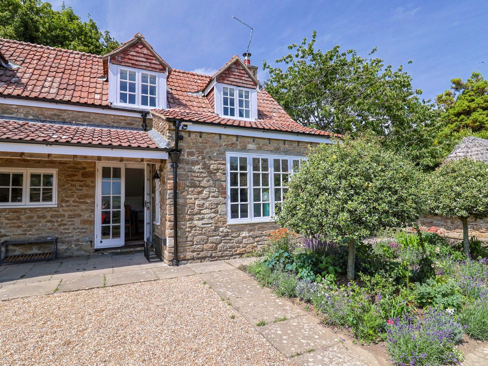 A house with windows and a garden at Tithe Barn Cottage in Litton Cheney near Burton Bradstock