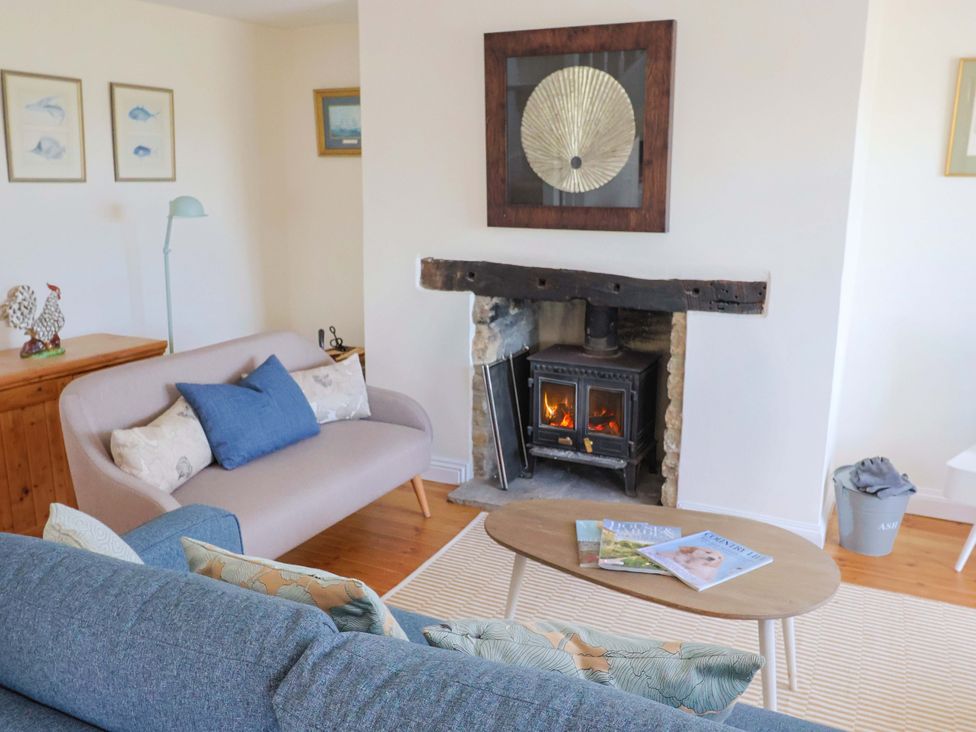 A living room with a sofa and fireplace at Tithe Barn Cottage, Litton Cheney near Burton Bradstock