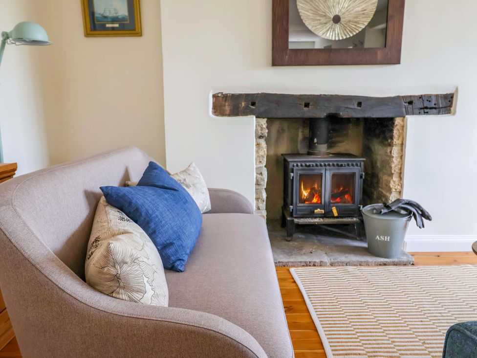 A living room with a sofa and fireplace at Tithe Barn Cottage in Litton Cheney near Burton Bradstock